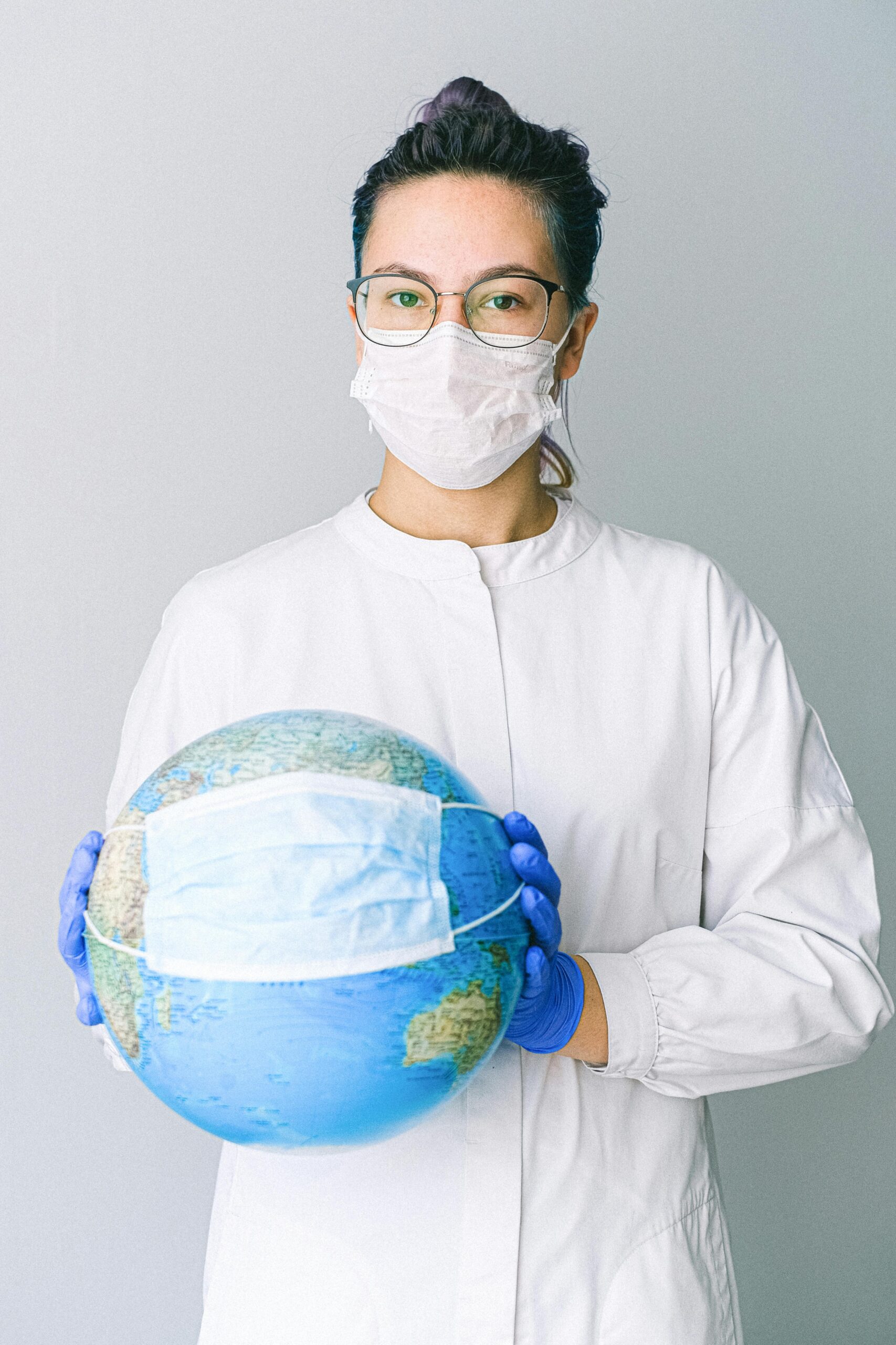 pexels-photo-4167541-4167541 Conceptual image of a doctor holding a globe with a mask, symbolizing global health.